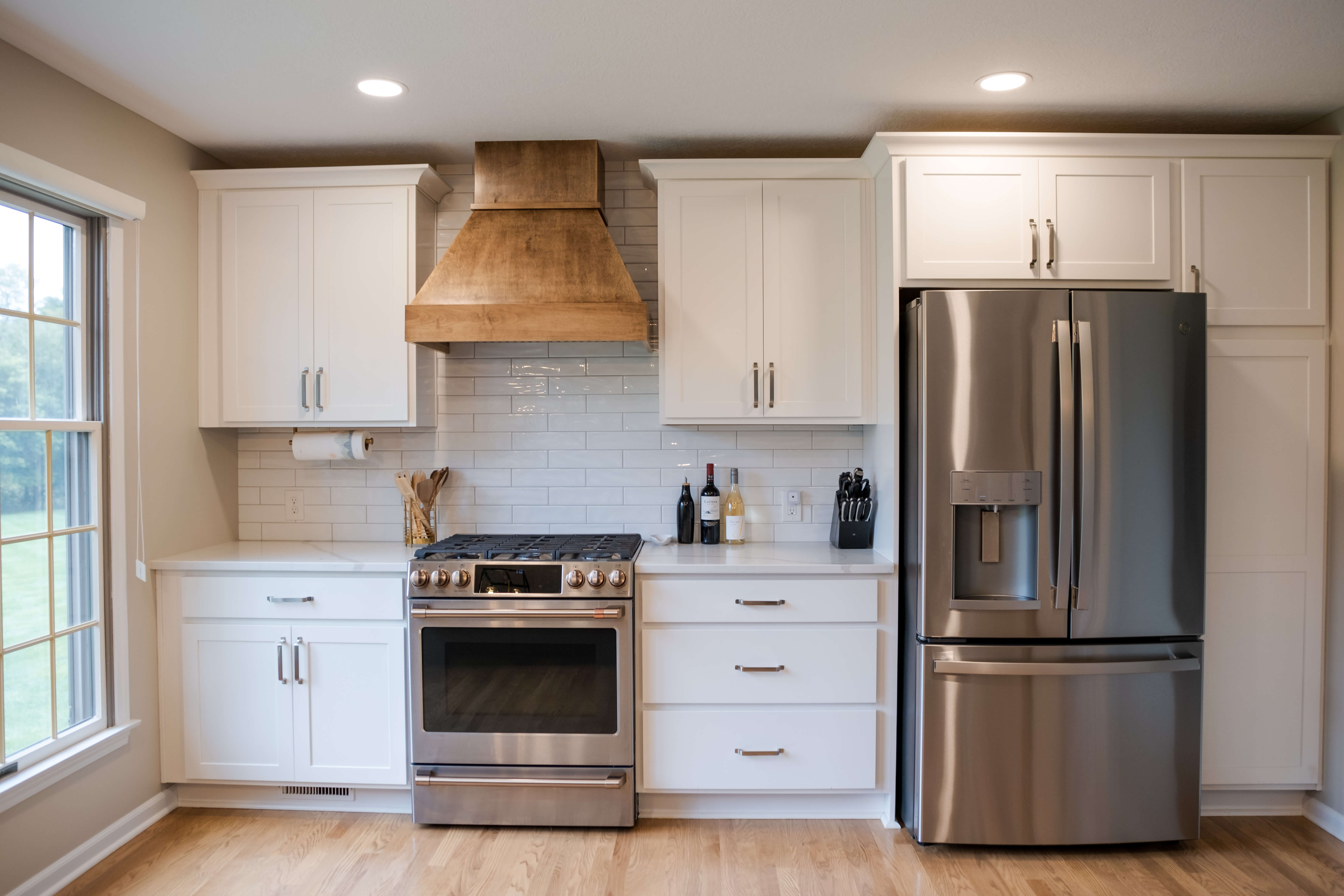 2022 Custom Built Kitchen Remodel. Beautiful white cabinets, with warm wood hood vent. Galley style against the wall.