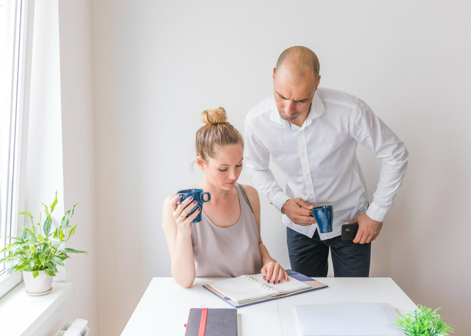 Two people holding coffee and examining an agenda