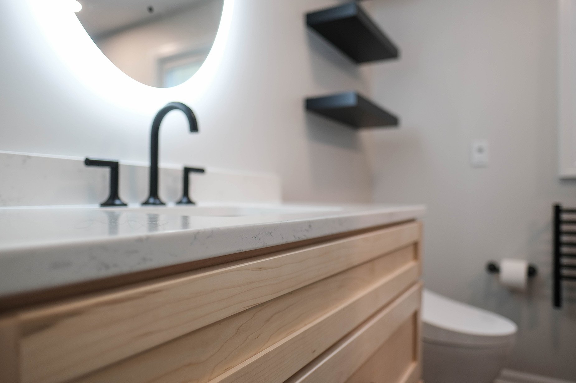 Beautiful remodeled bathroom with backlit mirror and black fixtures