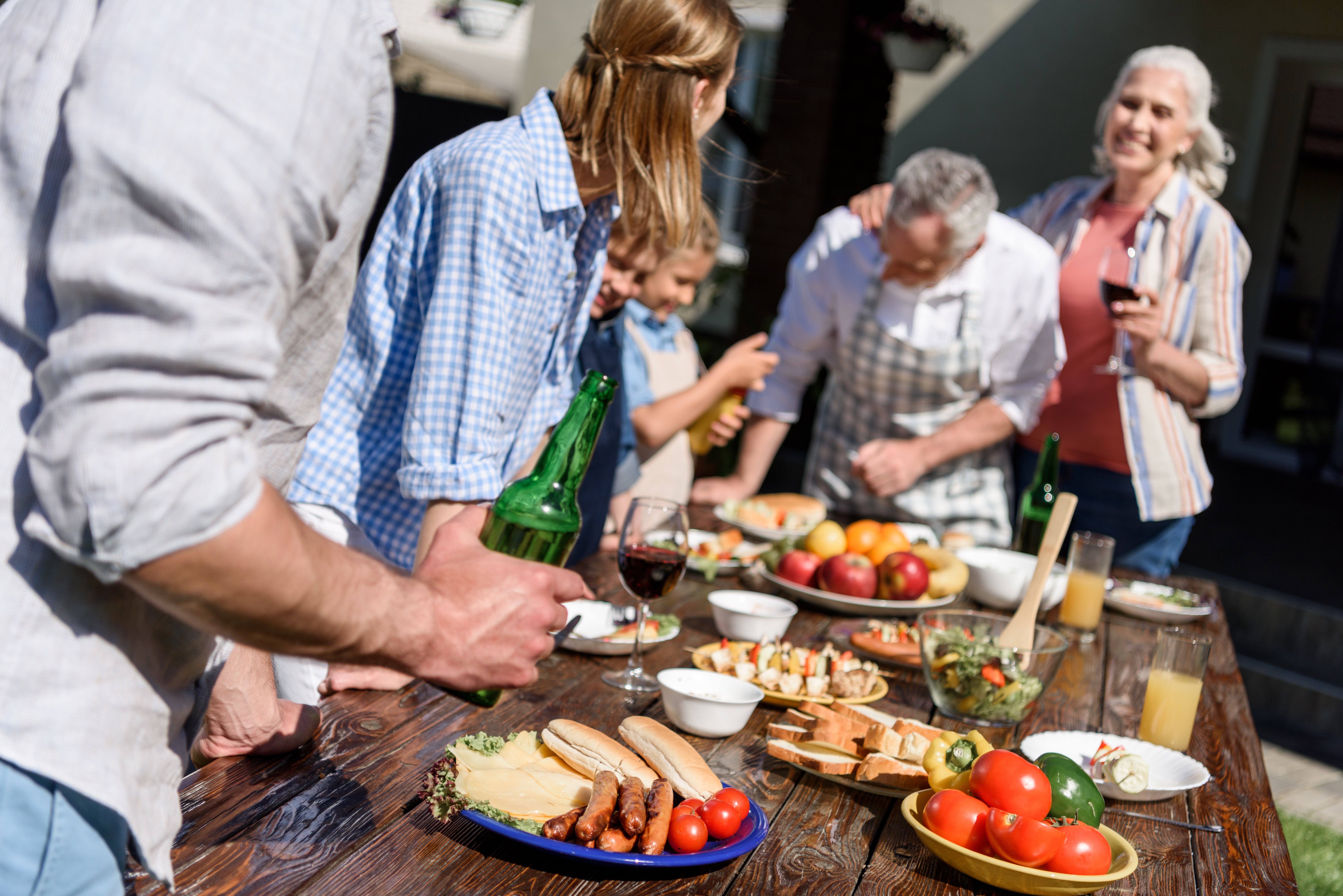 Group of friends gathering around a picnic table with food